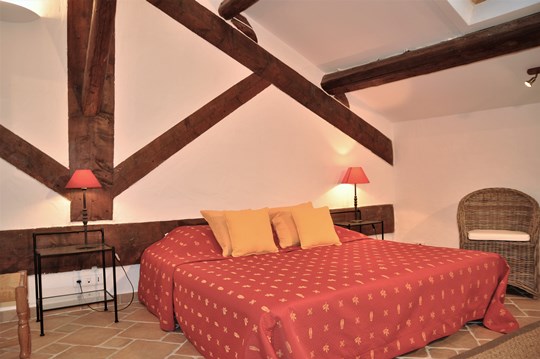 Mas des Oliviers at Moulin de la Roque, Noves, large Master bedroom, with cheerfull fabrics of Provence. Stunning original beam integrated in the wall